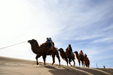 Visiteurs à dos de chameau dans les montagnes de sable de Mingsha au Gansu